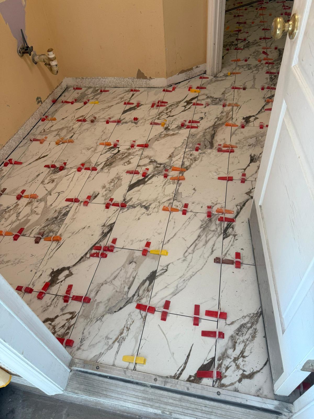 Marble-look floor tile installation aligned with precision leveling spacers