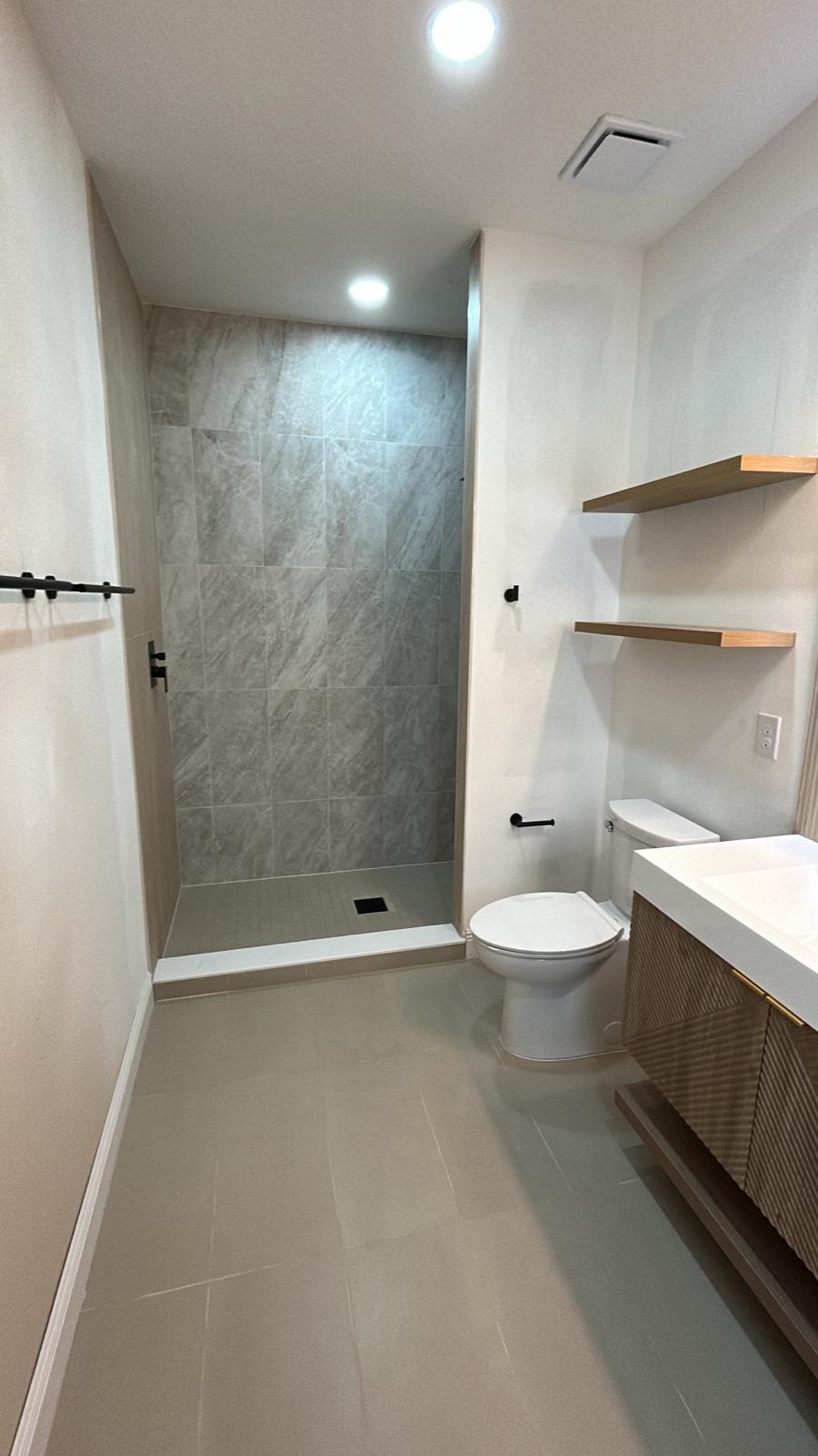 Finished bathroom with large-format shower surround and floating wood shelves