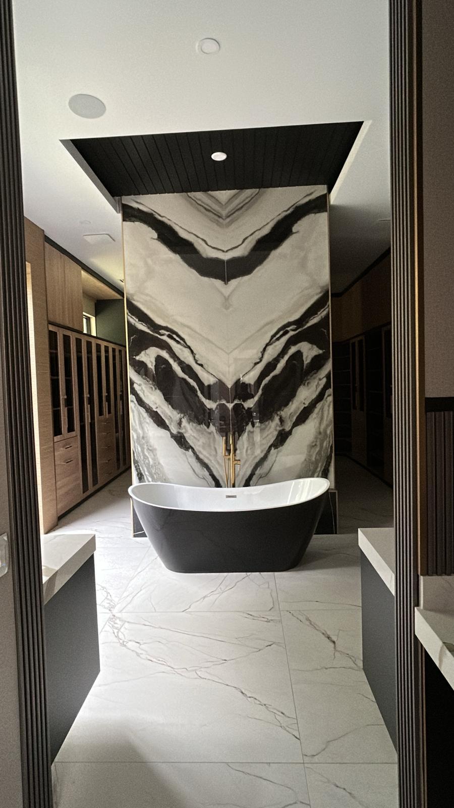 Freestanding black bathtub set against a dramatic black-and-white marble feature wall