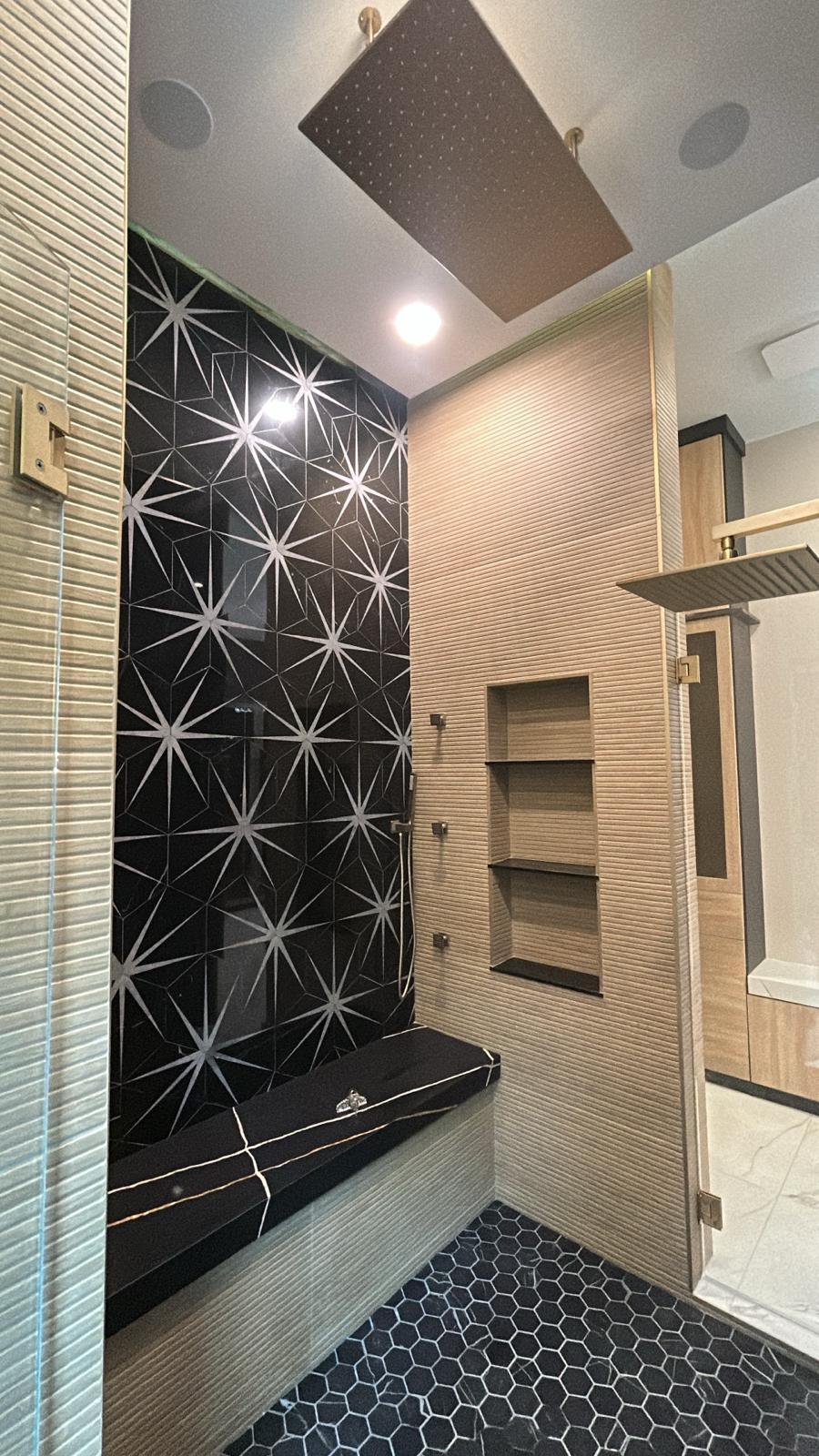 Shower with black star-pattern feature tile, fluted beige walls and hexagon floor tile