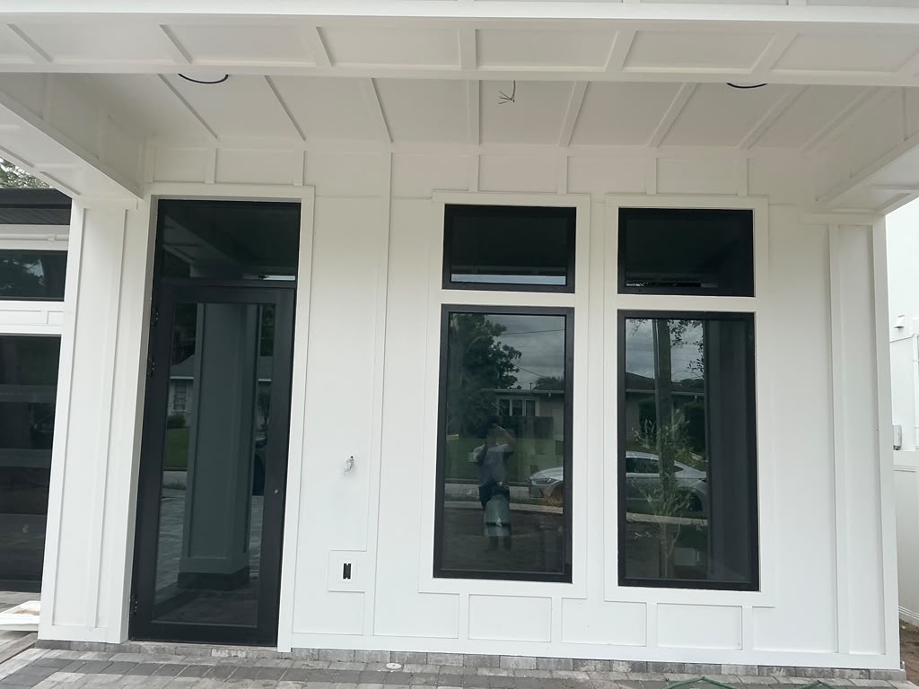Covered porch with white coffered ceiling, black-framed windows and glass door