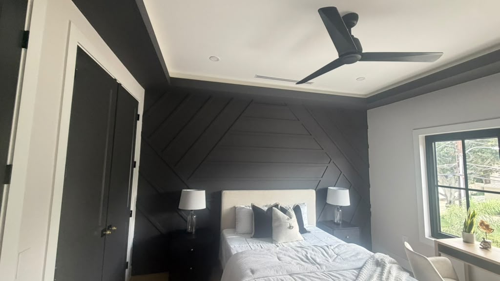 Bedroom with black chevron accent wall, tray ceiling and black ceiling fan